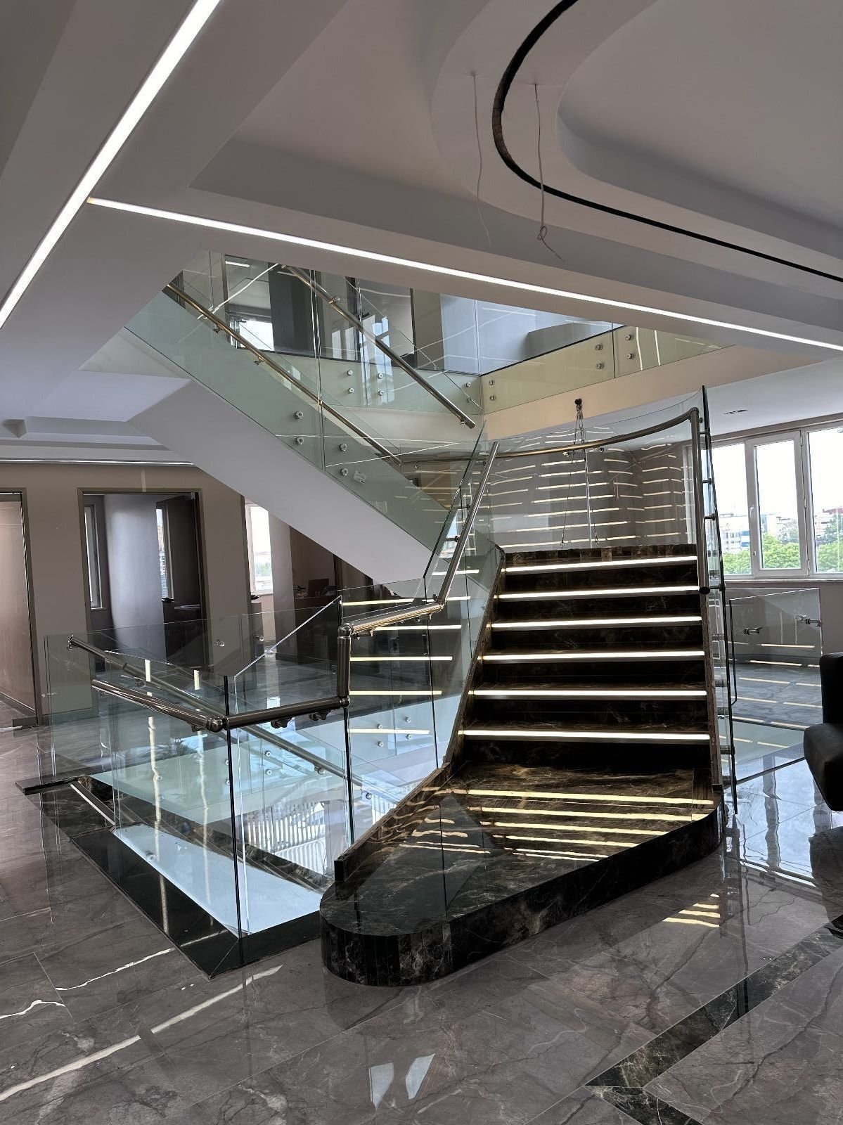 Escadaria em vidro e mármore no átrio da clínica
